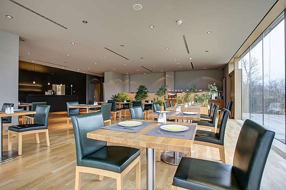 Moderner Frühstücksraum mit Holztischen, schwarzen Stühlen, großen Fenstern und Pflanzen. Helle, einladende Atmosphäre., © Centro Hotels Moderner Frühstücksraum mit Holztischen, schwarzen Stühlen, großen Fenstern und Pflanzen. Helle, einladende Atmosphäre., © Centro Hotels