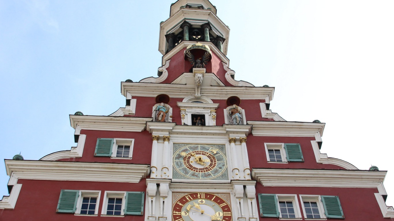 Fassade des Alten Rathauses in Esslingen mit einer gro&szlig;en Uhr, verzierten Fenstern und Figuren. Das Geb&auml;ude hat eine rote Fassade und gr&uuml;ne Fensterl&auml;den., &copy; Altes Rathaus Esslingen &copy;Fiona Flieder
