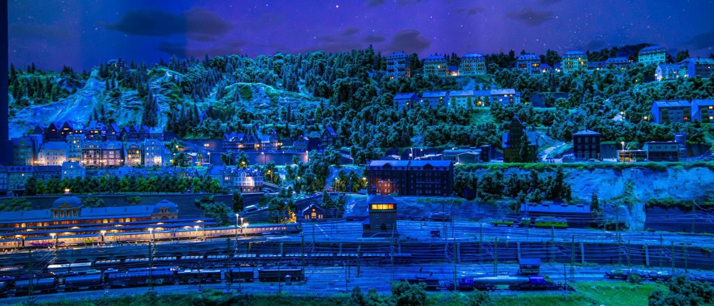 Eine detailreiche Modelllandschaft bei Nacht mit beleuchteten Gebäuden und einer Eisenbahnanlage im Vordergrund., © Stuttgart-Marketing GmbH, Sarah Schmid Eine detailreiche Modelllandschaft bei Nacht mit beleuchteten Gebäuden und einer Eisenbahnanlage im Vordergrund., © Stuttgart-Marketing GmbH, Sarah Schmid
