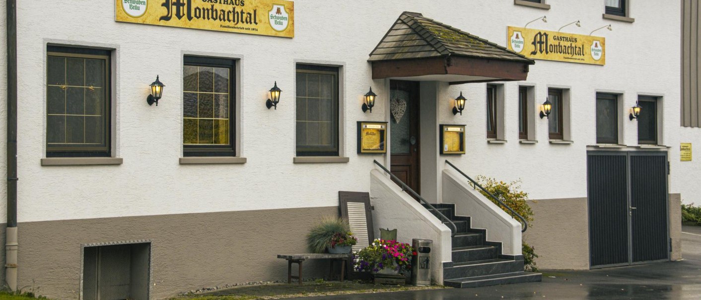 Eingang des Gasthauses Monbachtal mit Treppe, Blumendekoration und beleuchteten Laternen an der wei&szlig;en Fassade., &copy; Stuttgart Marketing GmbH, Sarah Schmid