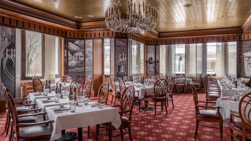 Elegantes Steakhouse mit weißen Tischdecken, Holzstühlen und Kronleuchter. Roter Teppichboden und große Fenster sorgen für eine warme Atmosphäre., © copyright by Kilian Blees Elegantes Steakhouse mit weißen Tischdecken, Holzstühlen und Kronleuchter. Roter Teppichboden und große Fenster sorgen für eine warme Atmosphäre., © copyright by Kilian Blees