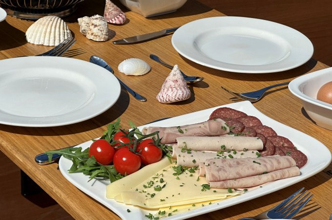 Ein gedeckter Frühstückstisch mit Wurst, Käse, Tomaten und Muscheln als Dekoration., © Cool-Tours StattReisen Ein gedeckter Frühstückstisch mit Wurst, Käse, Tomaten und Muscheln als Dekoration., © Cool-Tours StattReisen