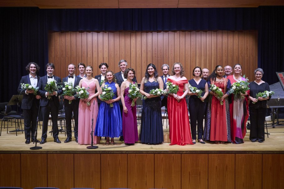 Eine Gruppe von Menschen in eleganter Abendkleidung steht auf einer B&uuml;hne und h&auml;lt Blumenstr&auml;u&szlig;e. Der Hintergrund ist eine Holzwand., &copy; www.peter-oppenlaender.de