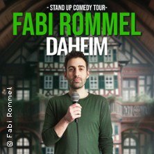 Ein Mann hält ein Mikrofon vor einem Fachwerkhaus. Text: Fabi Rommel - Daheim, Stand Up Comedy Tour., © links im Bild Ein Mann hält ein Mikrofon vor einem Fachwerkhaus. Text: Fabi Rommel - Daheim, Stand Up Comedy Tour., © links im Bild