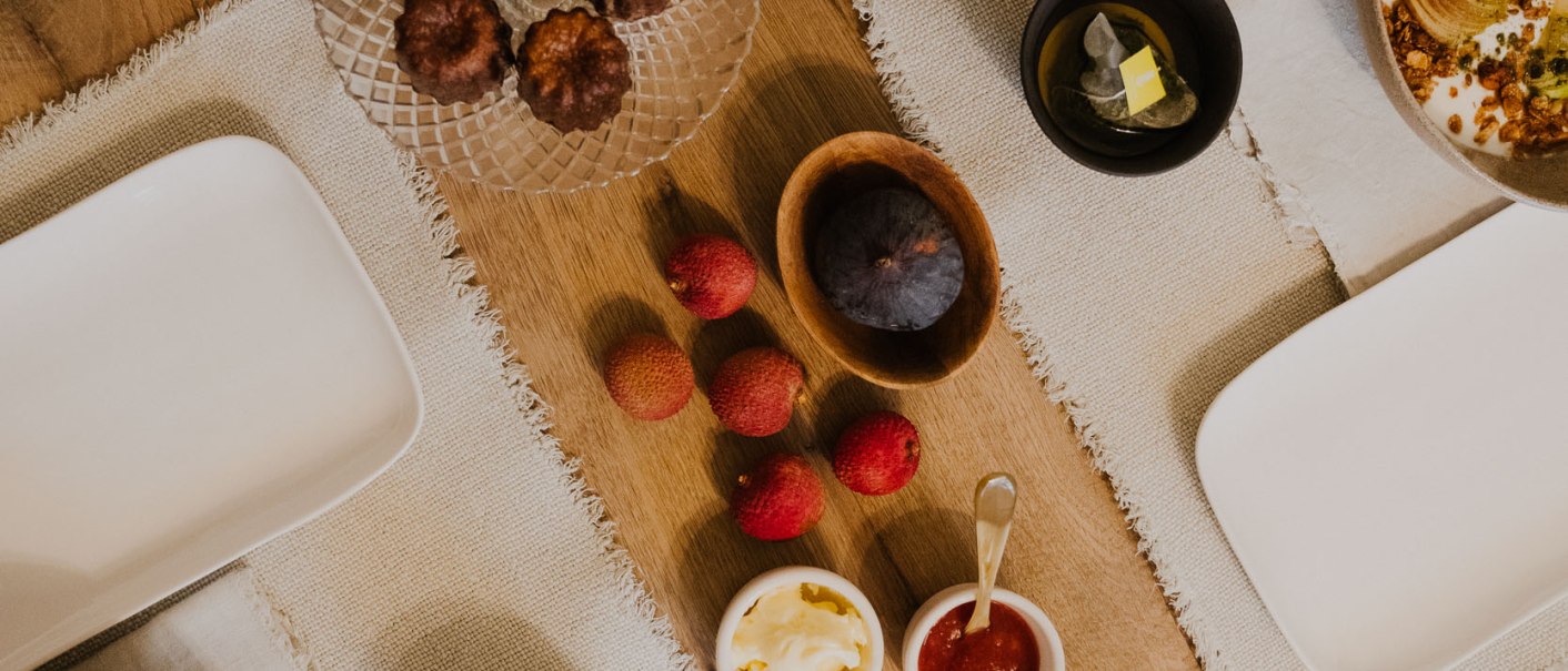 Ein gedeckter Tisch mit Gebäck, Joghurt mit Beeren, Saft, Tee, Marmelade, Butter und Obst auf Holzuntergrund., © Peter Oliver Wolff / DAS EDITH