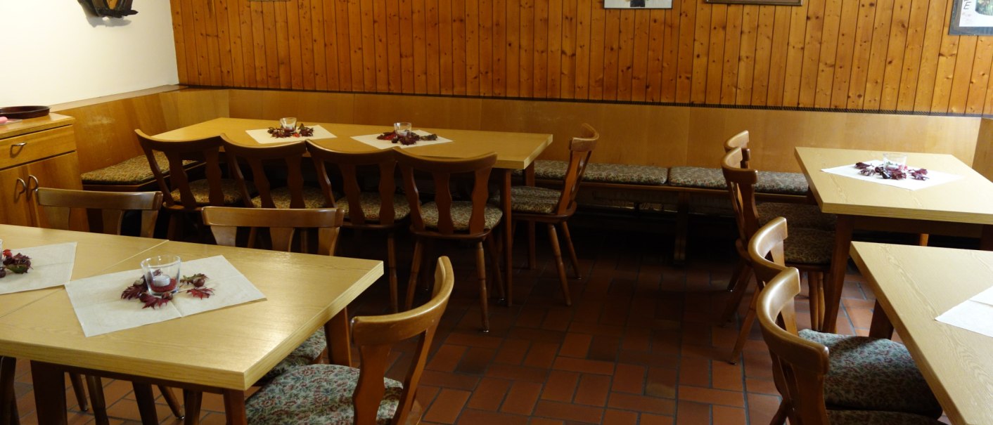 Ein gem&uuml;tlicher Gastraum mit Holztischen und St&uuml;hlen, dekoriert mit Bildern an einer holzvert&auml;felten Wand., &copy; Besenwirtschaft Familie Nerz