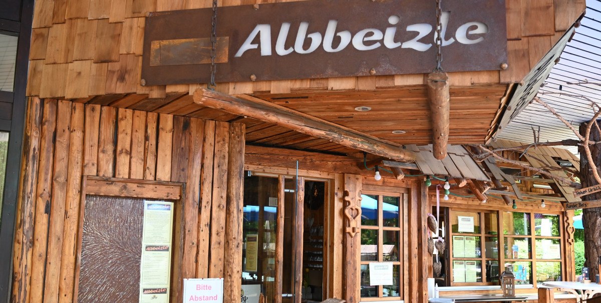 Rustikales Gebäude mit Holzverkleidung und dem Schild 'Albbeizle'. Der Eingang ist mit Holzdekor und Schildern gestaltet.