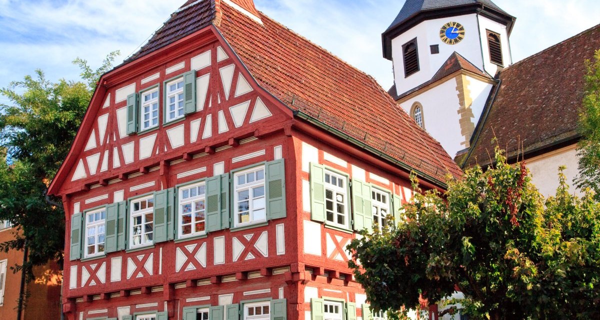 Fachwerkhaus mit grün-weißen Fensterläden und rotem Dach, daneben ein Kirchturm mit Uhr, bei blauem Himmel., © Waiblingen - Stuttgart-Marketing GmbH Fachwerkhaus mit grün-weißen Fensterläden und rotem Dach, daneben ein Kirchturm mit Uhr, bei blauem Himmel., © Waiblingen - Stuttgart-Marketing GmbH