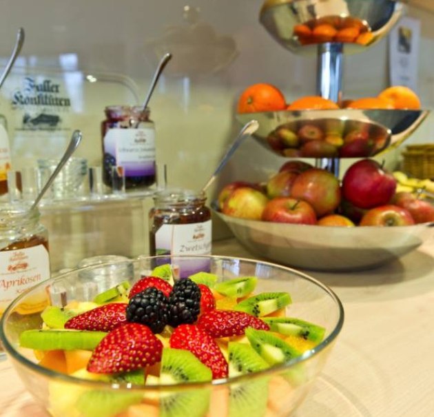 Ein Frühstücksbuffet mit frischem Obstsalat, Marmeladengläsern und einer Obstschale mit Äpfeln und Orangen., © Hotel Neuwirtshaus