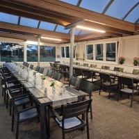 Ein überdachter Außenbereich mit langen, gedeckten Tischen und Stühlen, dekoriert mit kleinen Blumenvasen. Die Umgebung wirkt einladend und modern., © Restaurant Lingam Ein überdachter Außenbereich mit langen, gedeckten Tischen und Stühlen, dekoriert mit kleinen Blumenvasen. Die Umgebung wirkt einladend und modern., © Restaurant Lingam