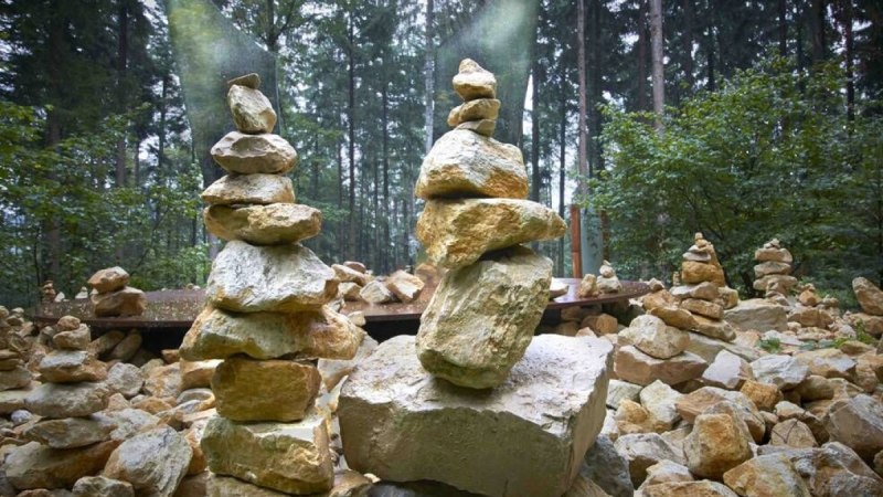 Ein großer Berg aus beigen Steinen. Im Vordergrund stehen zwei Türme aus aufeinandergestapelten Steinen. Jeder Turm hat eine Art Flügel aus Metall, man könnte einen Engel darin erkennen., © Schönblick - Christliches Gästezentrum Württemberg