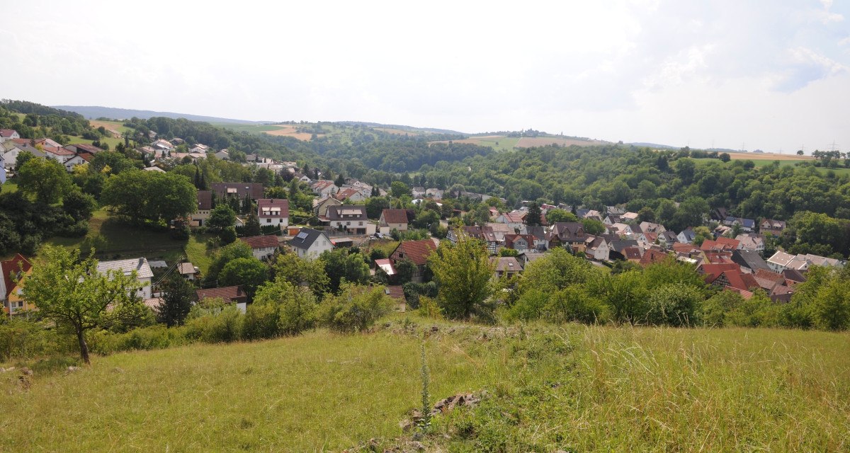 Panoramablick auf ein Dorf mit vielen Häusern, umgeben von grüner Landschaft und Hügeln unter einem bewölkten Himmel., © Land der 1000 Hügel - Kraichgau-Stromberg