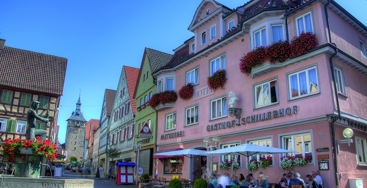 Hotel Schillerhof in einer malerischen Altstadt mit Fachwerkhäusern, einem Brunnen und Menschen, die im Freien sitzen. Sonniges Wetter und blauer Himmel., © Hotel Schillerhof Hotel Schillerhof in einer malerischen Altstadt mit Fachwerkhäusern, einem Brunnen und Menschen, die im Freien sitzen. Sonniges Wetter und blauer Himmel., © Hotel Schillerhof