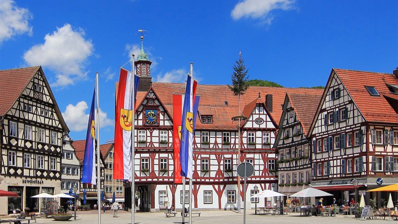 Historischer Marktplatz mit Fachwerkh&auml;usern, Fahnen und blauem Himmel in einer deutschen Stadt.