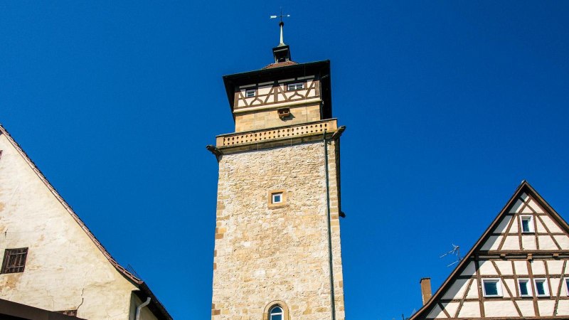 Der Hochwachturm in Waiblingen ragt zwischen zwei Fachwerkhäusern in den blauen Himmel empor., © SMG, Sarah Schmid Der Hochwachturm in Waiblingen ragt zwischen zwei Fachwerkhäusern in den blauen Himmel empor., © SMG, Sarah Schmid