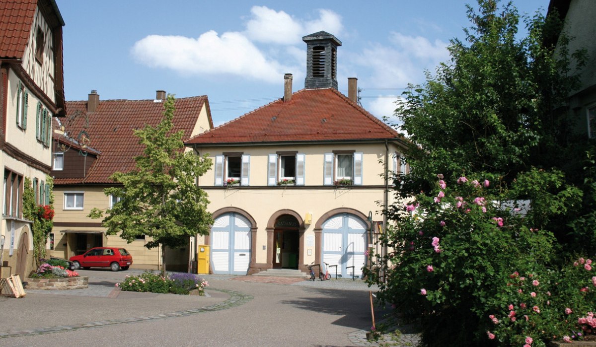 Das Rathaus in Ensingen mit rotem Ziegeldach und blauen Fensterläden, umgeben von blühenden Rosen und einem kleinen Platz., © Land der 1000 Hügel - Kraichgau-Stromberg Das Rathaus in Ensingen mit rotem Ziegeldach und blauen Fensterläden, umgeben von blühenden Rosen und einem kleinen Platz., © Land der 1000 Hügel - Kraichgau-Stromberg