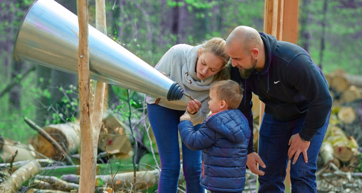 Eine Familie mit einem Kind untersucht einen großen Hörtrichter im Wald auf dem Herzog-Jäger-Pfad., © Natur.Nah. Schönbuch & Heckengäu Eine Familie mit einem Kind untersucht einen großen Hörtrichter im Wald auf dem Herzog-Jäger-Pfad., © Natur.Nah. Schönbuch & Heckengäu