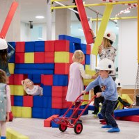 Kinder spielen auf einer Indoor-Baustelle mit bunten Schaumstoffbl&ouml;cken. Sie tragen Bauhelme und haben Spa&szlig; beim Bauen und Spielen., &copy; Julia Ochs