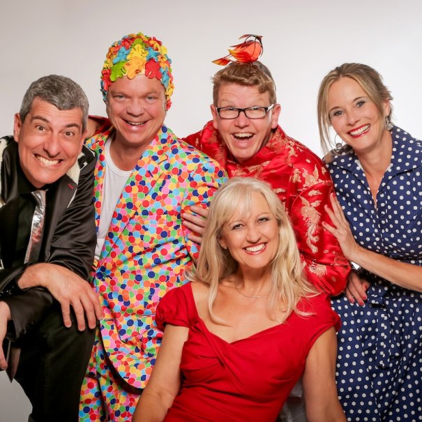 Fünf Personen in bunten, fröhlichen Outfits lächeln in die Kamera. Sie tragen farbenfrohe Kleidung und scheinen gut gelaunt zu sein., © Mauerwerk GmbH Fünf Personen in bunten, fröhlichen Outfits lächeln in die Kamera. Sie tragen farbenfrohe Kleidung und scheinen gut gelaunt zu sein., © Mauerwerk GmbH