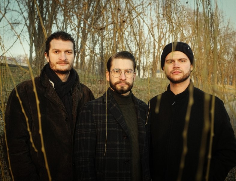 Drei Männer in Winterkleidung stehen in einem kahlen Wald und blicken ernst in die Kamera., © Interessengemeinschaft Kultur Sindelfingen / Böblingen e.V.