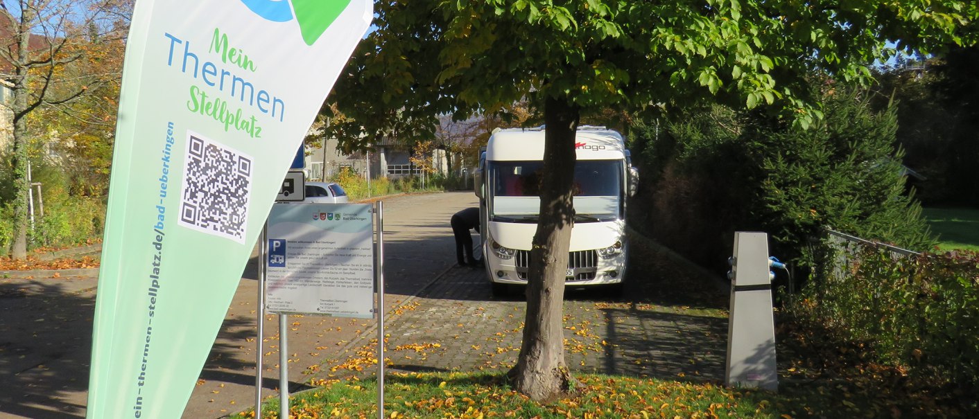 Wohnmobilstellplatz in Bad Überkingen mit einem geparkten Wohnmobil, Bäumen und einem Schild mit QR-Code und Informationen., © Archiv Gemeinde Bad Überkingen