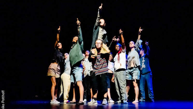 Eine Gruppe von Menschen steht auf einer Bühne und zeigt mit erhobenen Armen nach oben. Die Szene ist dramatisch beleuchtet., © Stadt Kornwestheim Kulturmanagement Eine Gruppe von Menschen steht auf einer Bühne und zeigt mit erhobenen Armen nach oben. Die Szene ist dramatisch beleuchtet., © Stadt Kornwestheim Kulturmanagement