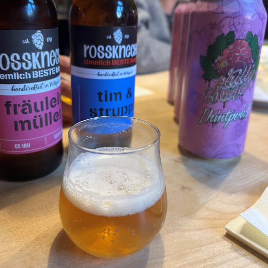 Verschiedene Bierflaschen und ein Glas Bier auf einem Tisch. Die Etiketten zeigen kreative Namen wie 'Fräulein Müller' und 'Tim & Struppi'., © Tourist Information und Ticket Service Ludwigsburg