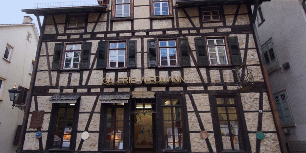 Fachwerkhaus mit der Aufschrift 'Galerie Wiedmann'. Das Gebäude hat mehrere Fenster mit grünen Fensterläden und eine Laterne an der Seite., © Galerie Wiedmann Fachwerkhaus mit der Aufschrift 'Galerie Wiedmann'. Das Gebäude hat mehrere Fenster mit grünen Fensterläden und eine Laterne an der Seite., © Galerie Wiedmann