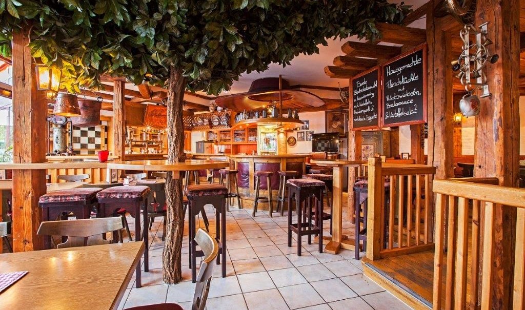 Gemütliche Bar mit Holzmöbeln, Baumdeko und Tafeln mit Speiseangeboten. Die Einrichtung wirkt rustikal und einladend., © Hotel Waldhorn Gemütliche Bar mit Holzmöbeln, Baumdeko und Tafeln mit Speiseangeboten. Die Einrichtung wirkt rustikal und einladend., © Hotel Waldhorn