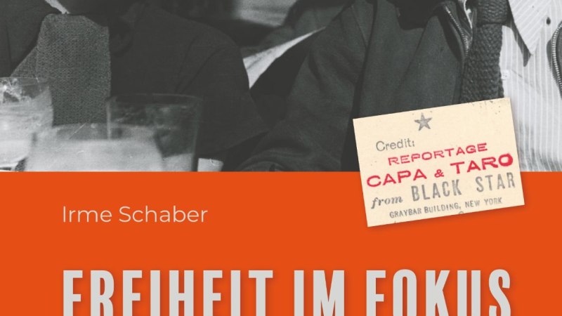 Buchcover mit Schwarz-Wei&szlig;-Foto von zwei lachenden Personen. Der Titel 'Freiheit im Fokus' ist in gro&szlig;en Buchstaben auf orangem Hintergrund.