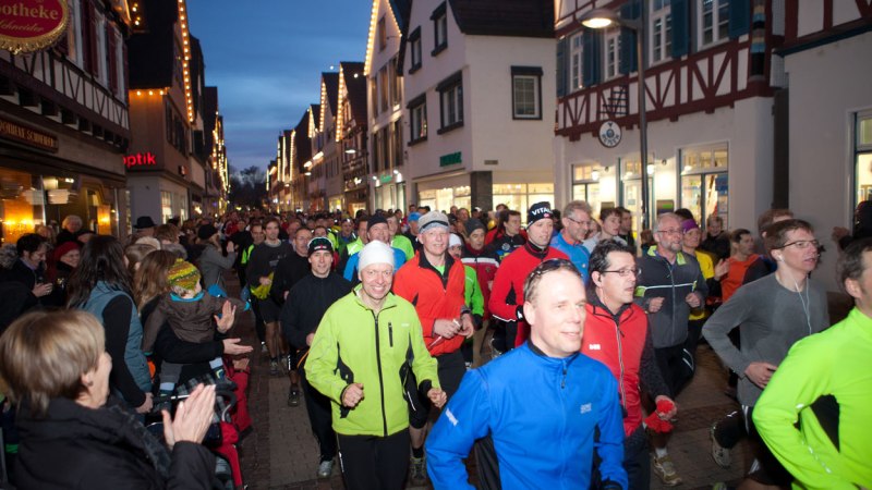 Menschenmengen laufen durch eine festlich beleuchtete Altstadtstraße beim Silvesterlauf. Zuschauer applaudieren am Straßenrand., © © Thomas Kaltenecker Menschenmengen laufen durch eine festlich beleuchtete Altstadtstraße beim Silvesterlauf. Zuschauer applaudieren am Straßenrand., © © Thomas Kaltenecker