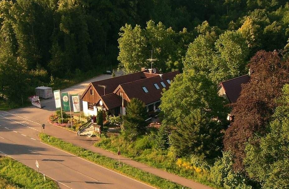 Luftaufnahme eines Geb&auml;udes am Waldrand, umgeben von B&auml;umen. Eine Stra&szlig;e f&uuml;hrt am Geb&auml;ude vorbei., &copy; WeingutKr&auml;uterb&uuml;hl