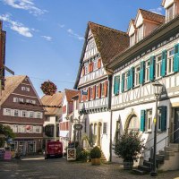 Fachwerkhäuser mit blauen Fensterläden in einer sonnigen Altstadtstraße, dekoriert mit Blumen. Kopfsteinpflaster und klare Himmel im Hintergrund., © Stuttgart-Marketing GmbH, Sarah Schmid Fachwerkhäuser mit blauen Fensterläden in einer sonnigen Altstadtstraße, dekoriert mit Blumen. Kopfsteinpflaster und klare Himmel im Hintergrund., © Stuttgart-Marketing GmbH, Sarah Schmid