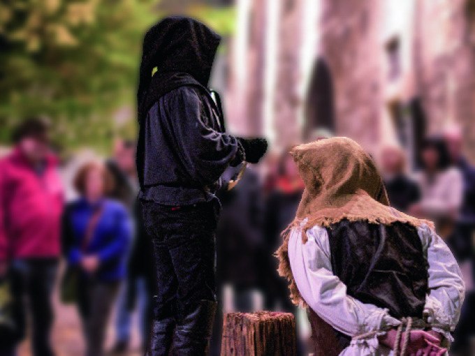 Mittelalterliche Szene mit zwei Personen in historischer Kleidung, eine kniet vor einem Holzblock, während die andere daneben steht. Zuschauer im Hintergrund., © Esslinger Stadtmarketing & Tourismus GmbH Mittelalterliche Szene mit zwei Personen in historischer Kleidung, eine kniet vor einem Holzblock, während die andere daneben steht. Zuschauer im Hintergrund., © Esslinger Stadtmarketing & Tourismus GmbH