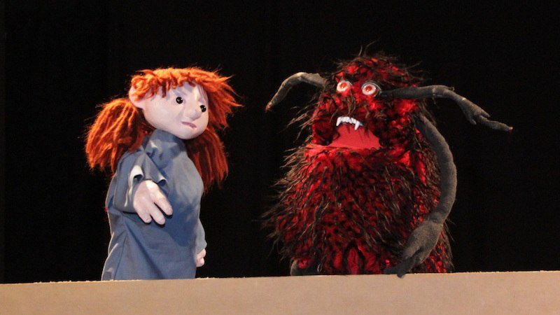 Zwei Puppen auf einer Bühne: eine mit roten Haaren und blauer Kleidung, die andere ein zotteliges, rotes Monster mit Hörnern., © FILharmonie Filderstadt Zwei Puppen auf einer Bühne: eine mit roten Haaren und blauer Kleidung, die andere ein zotteliges, rotes Monster mit Hörnern., © FILharmonie Filderstadt
