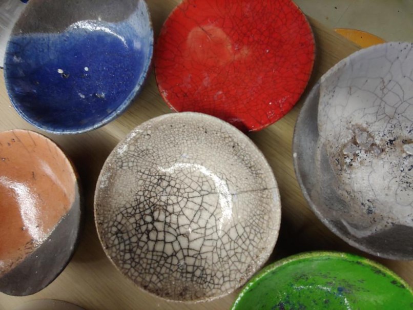 Bunte Raku-Keramikschalen in Blau, Rot, Weiß, Orange und Grün mit charakteristischen Rissen auf einem Tisch angeordnet., © Kunstschule Labyrinth