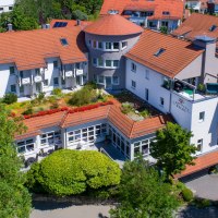 Das Hotel Landhaus Feckl zeigt eine Außenansicht mit roten Dächern, Balkonen und einem gepflegten Garten. Umgeben von Bäumen und einem gepflasterten Weg., © Landhaus Franz Feckl