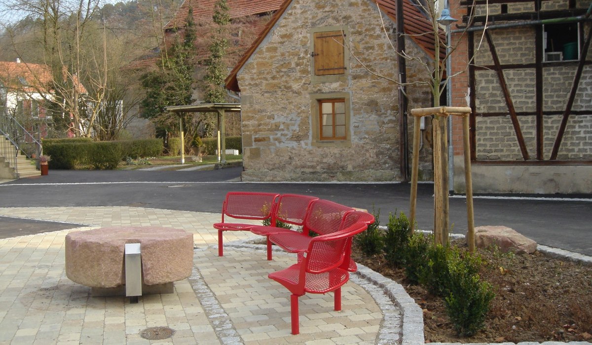 Gepflasterter Platz mit roten Bänken und rundem Steintisch, umgeben von Fachwerkhäusern und Bäumen. Datum auf dem Bild: 18.12.2007., © Land der 1000 Hügel - Kraichgau-Stromberg