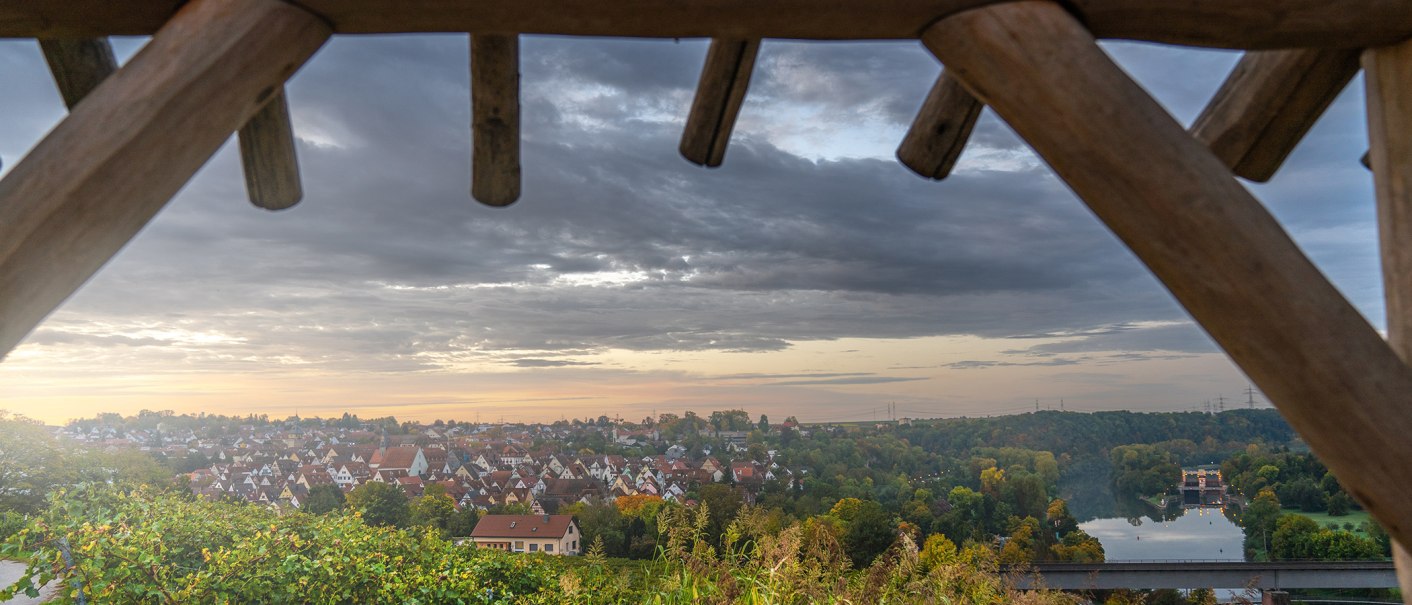 Blick von einer Plattform auf eine Stadt bei Sonnenuntergang. Im Vordergrund Holzbalken, im Hintergrund Häuser, ein Fluss und eine Brücke., © SMG, Martina Denker Blick von einer Plattform auf eine Stadt bei Sonnenuntergang. Im Vordergrund Holzbalken, im Hintergrund Häuser, ein Fluss und eine Brücke., © SMG, Martina Denker