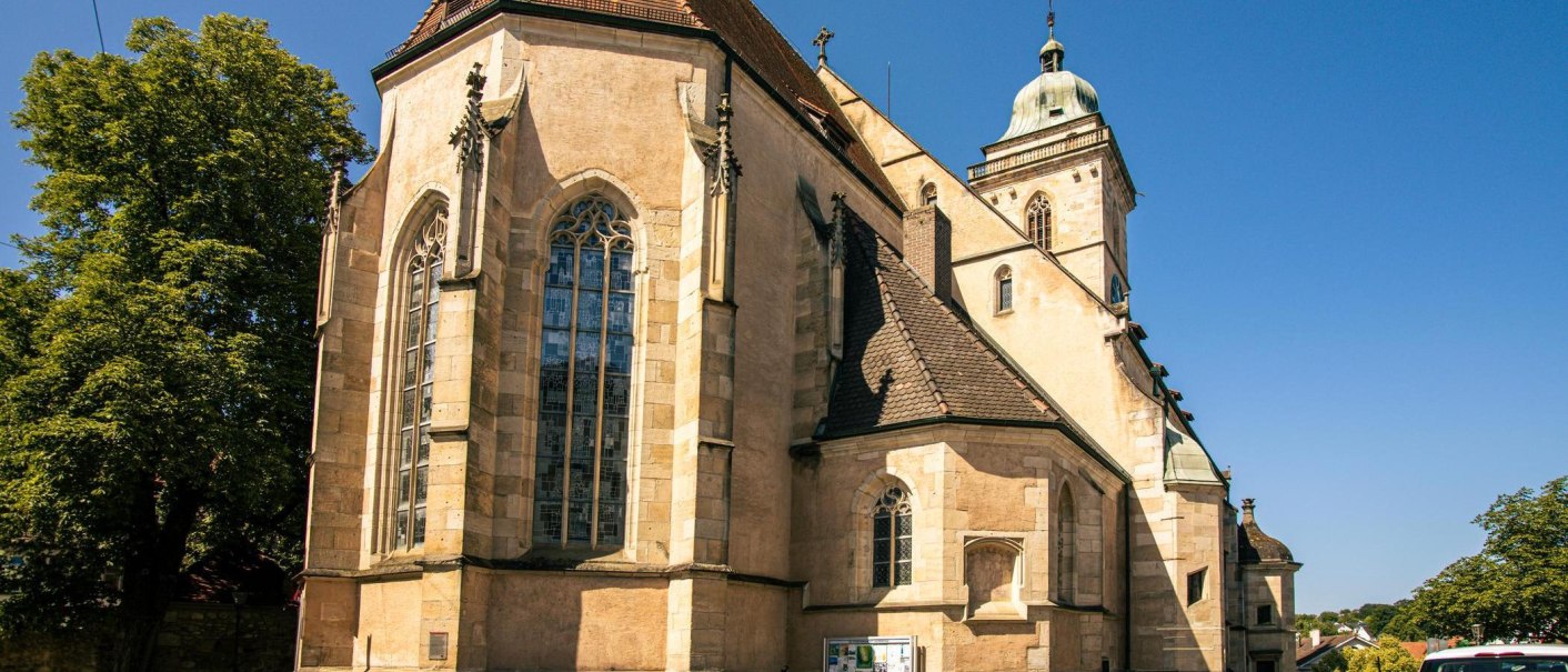 Die Laurentiuskirche in N&uuml;rtingen, ein historisches Geb&auml;ude mit gotischen Fenstern und einem Turm, bei strahlend blauem Himmel., &copy; Stuttgart-Marketing GmbH, Sarah Schmid