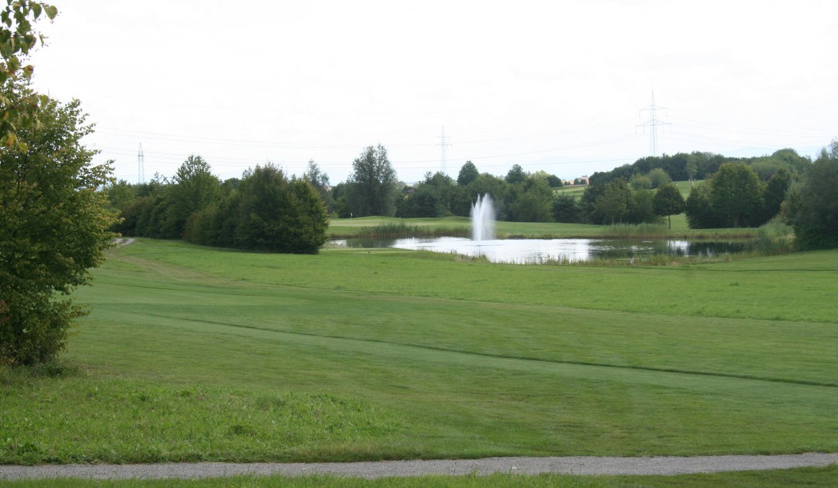 Grüne Wiese mit einem Teich und einem Springbrunnen im Hintergrund, umgeben von Bäumen und Stromleitungen., © Natur.Nah. Schönbuch & Heckengäu Grüne Wiese mit einem Teich und einem Springbrunnen im Hintergrund, umgeben von Bäumen und Stromleitungen., © Natur.Nah. Schönbuch & Heckengäu