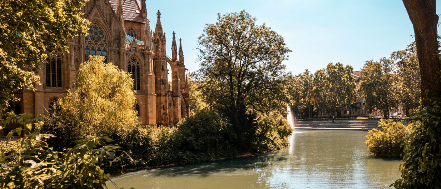 Die Johanneskirche am Feuersee, umgeben von Bäumen und Wasser, bei sonnigem Wetter., © SMG, Sarah Schmid Die Johanneskirche am Feuersee, umgeben von Bäumen und Wasser, bei sonnigem Wetter., © SMG, Sarah Schmid