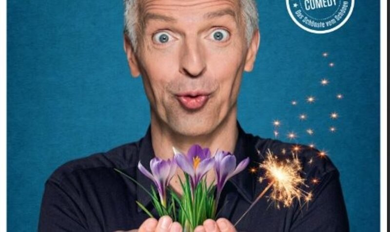 Ein Mann mit überraschter Mimik hält Krokusse und eine Wunderkerze vor einem blauen Hintergrund. Oben rechts steht "Comedy"., © Touristik Bad Wildbad GmbH Ein Mann mit überraschter Mimik hält Krokusse und eine Wunderkerze vor einem blauen Hintergrund. Oben rechts steht "Comedy"., © Touristik Bad Wildbad GmbH