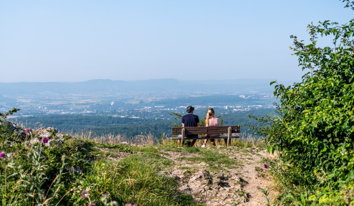 Zwei Personen sitzen auf einer Bank und genießen die Aussicht auf eine weite Landschaft unter klarem Himmel., © TMBW, Gregor Lengler Zwei Personen sitzen auf einer Bank und genießen die Aussicht auf eine weite Landschaft unter klarem Himmel., © TMBW, Gregor Lengler