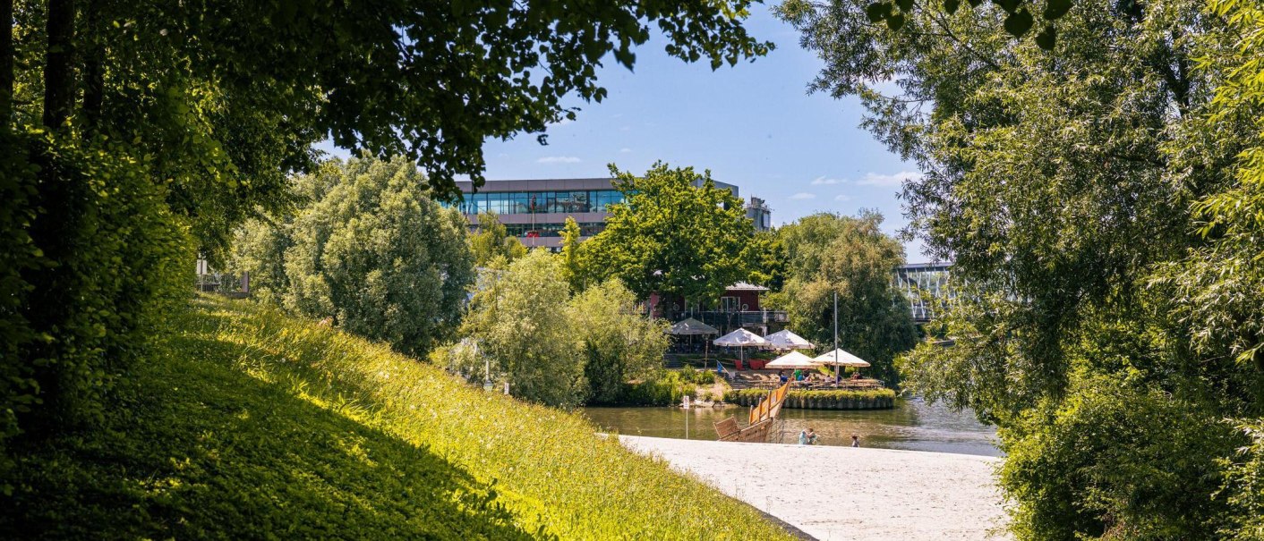 Ein idyllischer Strand am Neckar in Remseck, umgeben von üppigem Grün und einem modernen Gebäude im Hintergrund., © Stuttgart-Marketing GmbH, Sarah Schmid Ein idyllischer Strand am Neckar in Remseck, umgeben von üppigem Grün und einem modernen Gebäude im Hintergrund., © Stuttgart-Marketing GmbH, Sarah Schmid