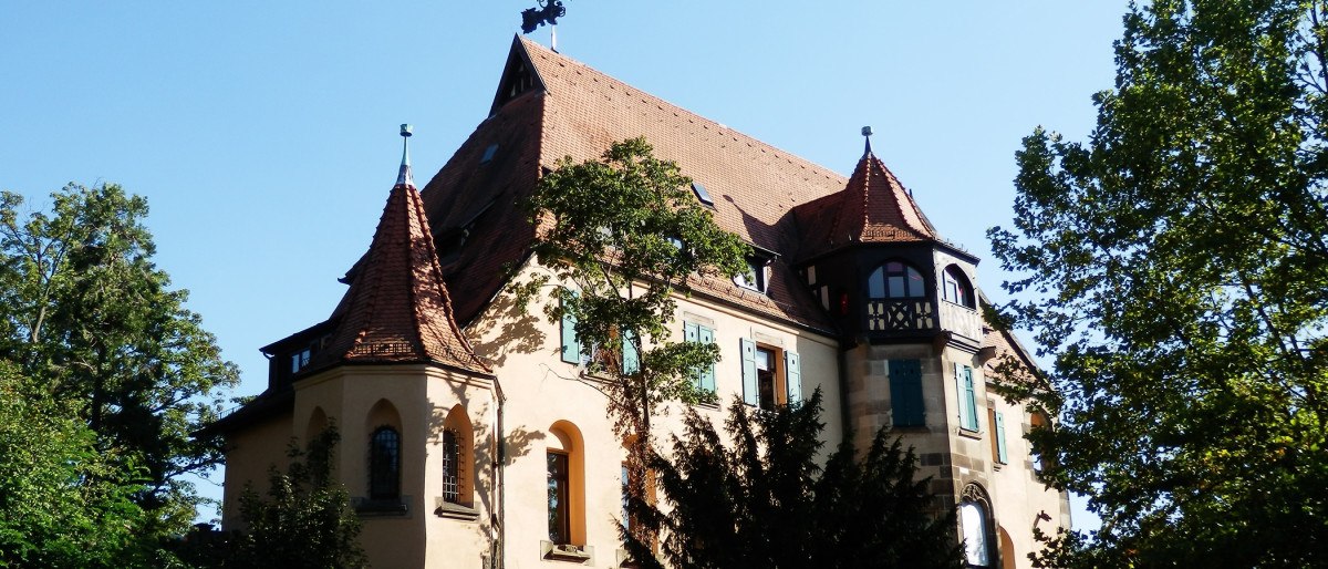 Die Villa Hauf ist ein historisches Gebäude mit Türmen und roten Ziegeldächern, umgeben von Bäumen und strahlend im Sonnenlicht., © Stuttgart-Marketing GmbH Die Villa Hauf ist ein historisches Gebäude mit Türmen und roten Ziegeldächern, umgeben von Bäumen und strahlend im Sonnenlicht., © Stuttgart-Marketing GmbH