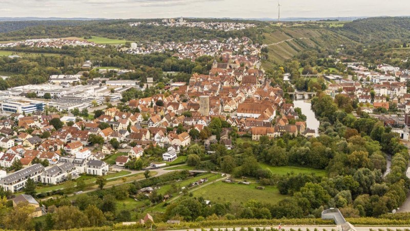 Panoramablick auf Besigheim, umgeben von grünen Weinbergen und Fluss. Historische Gebäude und moderne Strukturen prägen das Stadtbild., © SMG, Sarah Schmid Panoramablick auf Besigheim, umgeben von grünen Weinbergen und Fluss. Historische Gebäude und moderne Strukturen prägen das Stadtbild., © SMG, Sarah Schmid