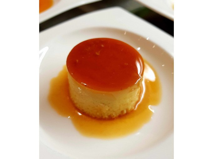Ein Karamellflan auf einem weißen Teller, glänzend und mit einer Schicht Karamell überzogen., © Kultweine-Kochwelten-Kunstücke - Kochschule Sonja Lenz Ein Karamellflan auf einem weißen Teller, glänzend und mit einer Schicht Karamell überzogen., © Kultweine-Kochwelten-Kunstücke - Kochschule Sonja Lenz