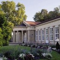 Der Kursaal Bad Cannstatt mit klassischer Architektur, großen Fenstern und einem gepflegten Garten im Vordergrund, umgeben von Bäumen., © Stuttgart-Marketing GmbH