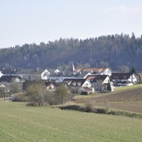 L&auml;ndliche Szene mit H&auml;usern in Nufringen, umgeben von Feldern und einem Wald im Hintergrund unter klarem Himmel., &copy; Natur.Nah. Sch&ouml;nbuch & Heckeng&auml;u